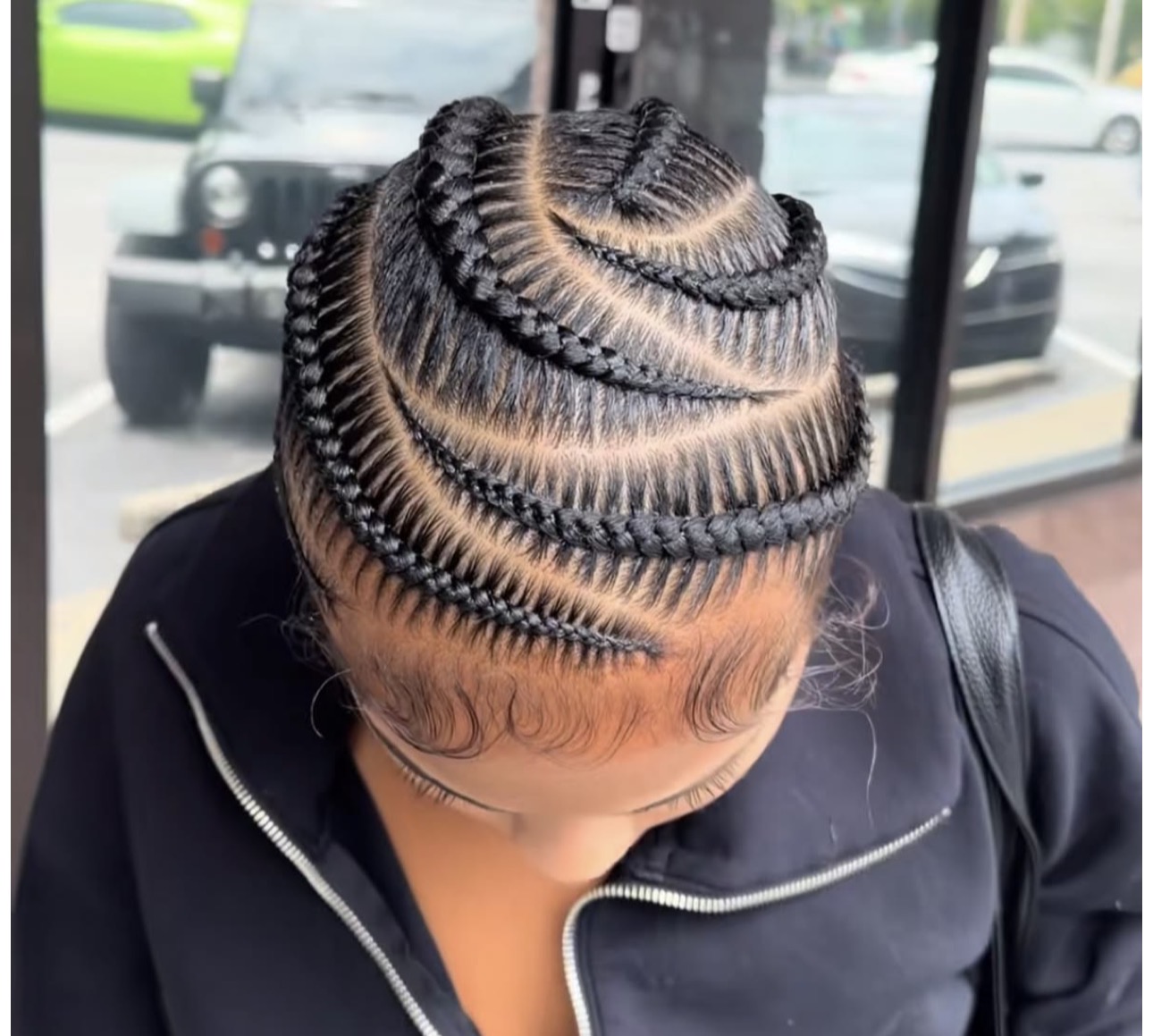 Top view of sleek, geometric stitch feed in braids with crisp curved parts on a client at The Braiders Lounge in Somerset, NJ.
